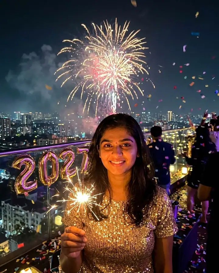 AI example of a woman holding a sparkler on a rooftop with fireworks behind